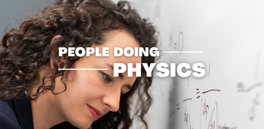 Woman with long curly hair writes physics formulas on a whiteboard