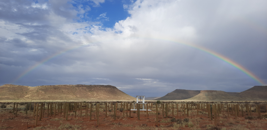 a rainbow over an instrument in the middle of a desert