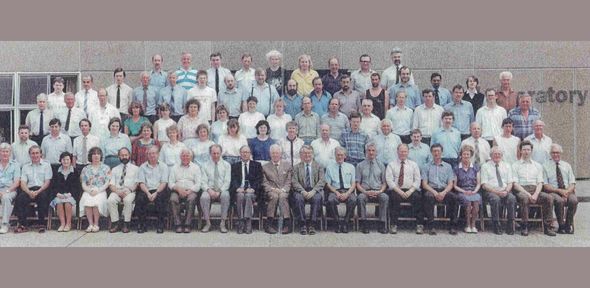 School photo-style image showing staff members sitting in rows in front of the Cavendish Laboratory.
