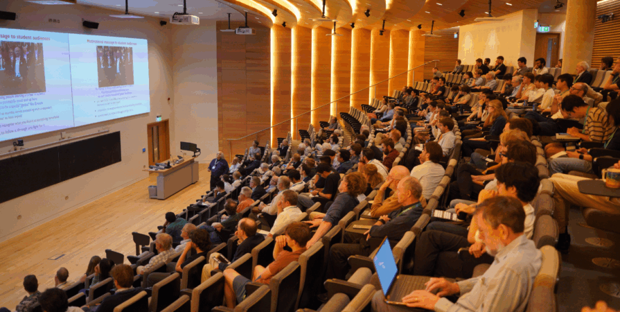 view from the audience of a speaker giving a talk in the ray dolby auditorium