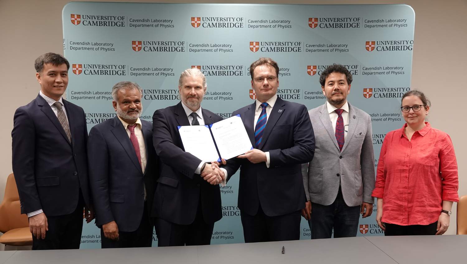 six people representing BMU and the Cavendish. The two men in the centre are shaking hands and holding the signed agreement. 